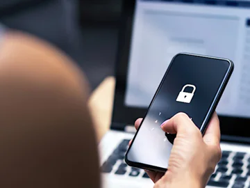 A person holding a mobile phone displaying a padlock symbol