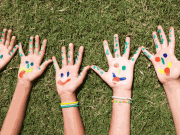 Hands with colourful smiling faces painted on them