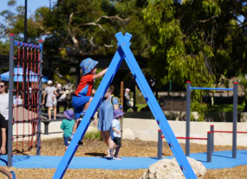 A young child climbing on an a-frame playground.