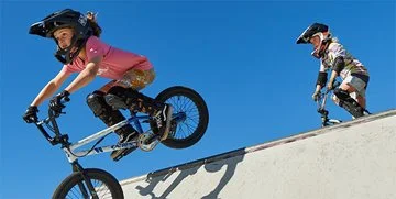 Two children ride BMX bikes at a bike park