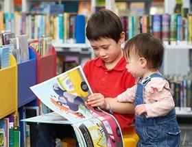 Two young children looking at a children's picture book