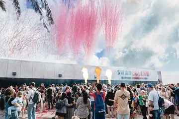 Crowds of people watch the daylight fireworks display.