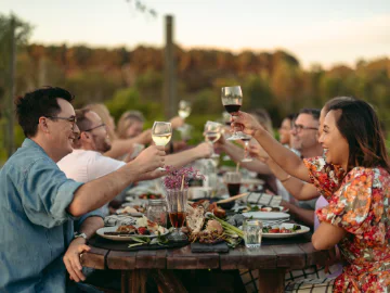A group of people sit at a table and enjoy a meal and drinks.