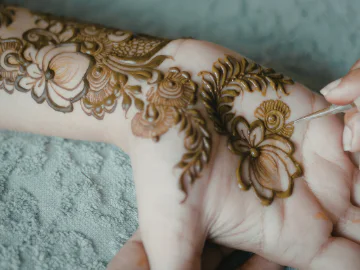 Henna designs being drawn on an open palm