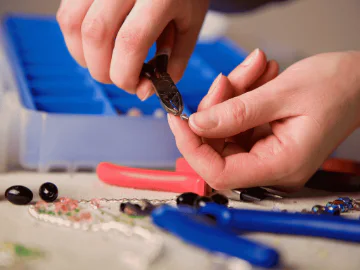 Hand holding plyers to form a piece of jewelry