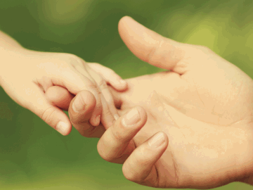 An adult hand holding a childs hand