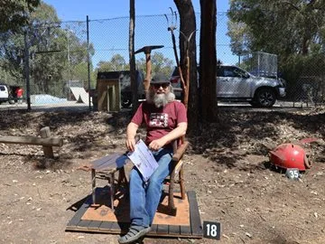 Scott McDonald sitting on his winning art piece the Farmer's Throne and side table