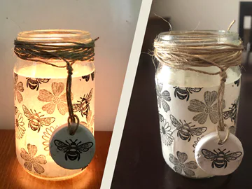 A pair of candles wrapped in candle holders adorned with bees
