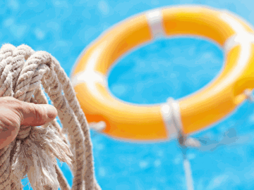 A person holding a rope and a lifesaver in a body of water