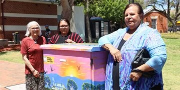 Artists next to a NBN node which has been wrapped in their art